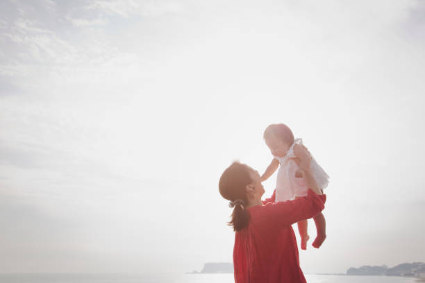 母と赤ちゃんの女の子が海辺でリラックス - 親子 ストックフォトと画像
