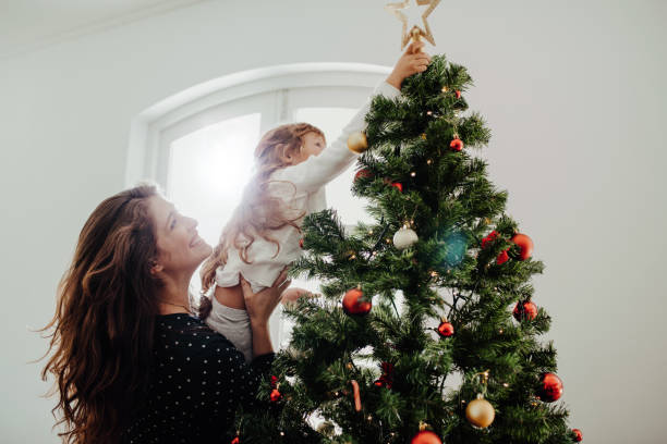 moeder en kind kerstboom versieren. - vrouw kerstboom versieren stockfoto's en -beelden