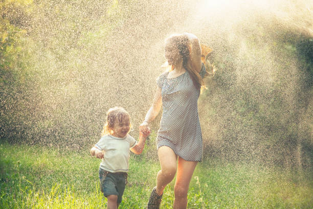 moeder en kind wordt uitgevoerd in de regen - rain woman sun stockfoto's en -beelden