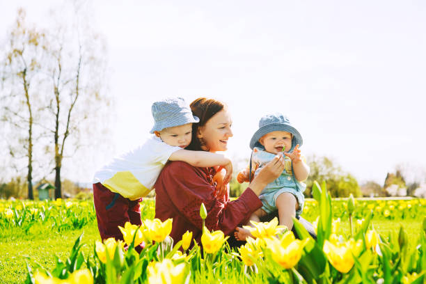 Mother and children among yellow tulips flowers. Mother and children among yellow tulips flowers. Woman with her kids playing outdoors in spring park. Family walking on nature. Image of Mother's Day, Easter. Tulip field in Arboretum, Slovenia. arboretum stock pictures, royalty-free photos & images