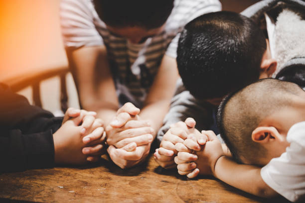 Mother and children praying and praising God at home stock photo