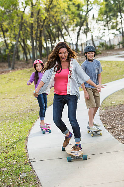 Mother (30s) and children (9 and 13 years), riding skateboards.  Mixed race Korean / Caucasian.