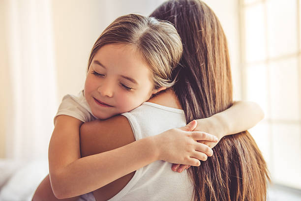 Mother and daughter at home Beautiful young woman and her charming little daughter are hugging and smiling embracing stock pictures, royalty-free photos & images