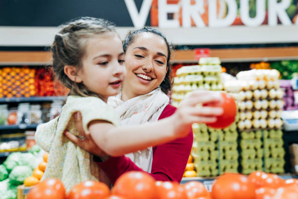 Mother and daughter buying groceries at store stock photo