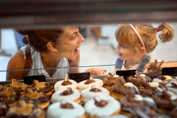 Mother and daughter buying yummy donuts together stock photo
