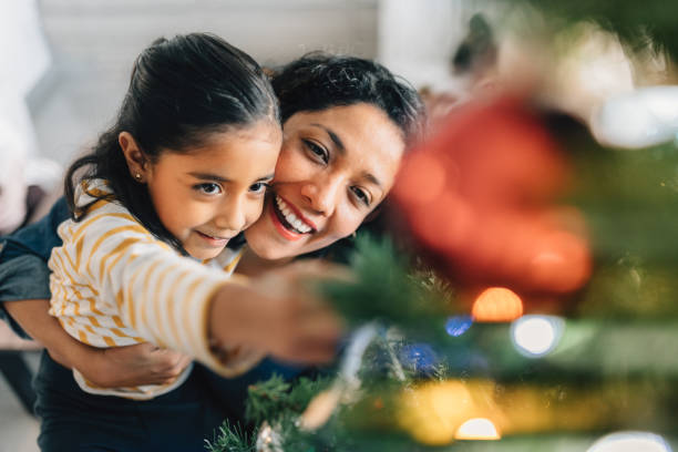 moeder en dochter versieren kerstboom - vrouw kerstboom versieren stockfoto's en -beelden