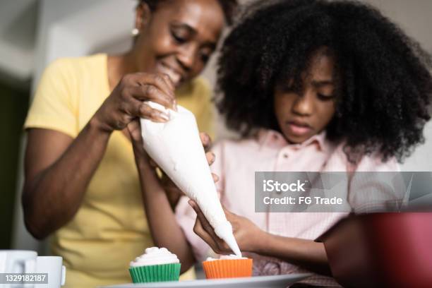 Mother and daughter decorating cupcakes together at home