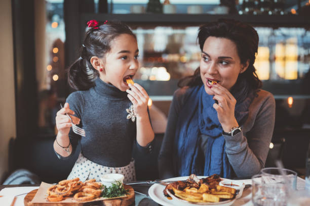 Mother and daughter enjoying nice dinner together Mother and daughter enjoying lunch in restaurant kid friendly restaurant stock pictures, royalty-free photos & images