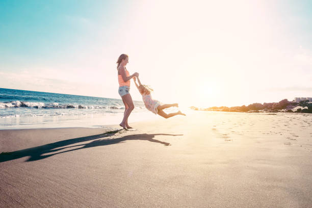 мать и дочь весело провести время на тропическом пляже - мама играет со своим ребенком в отпуске рядом с океаном - семейный образ жизни и люб� - england australia стоковые фото и изображения