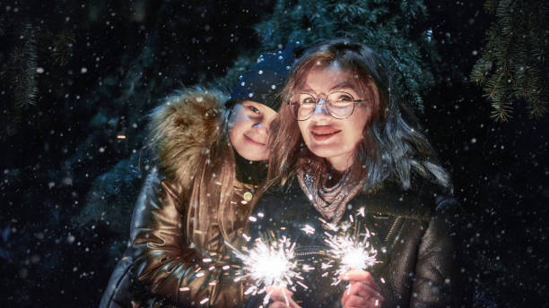 Mother and daughter holding burning sparklers outside stock photo