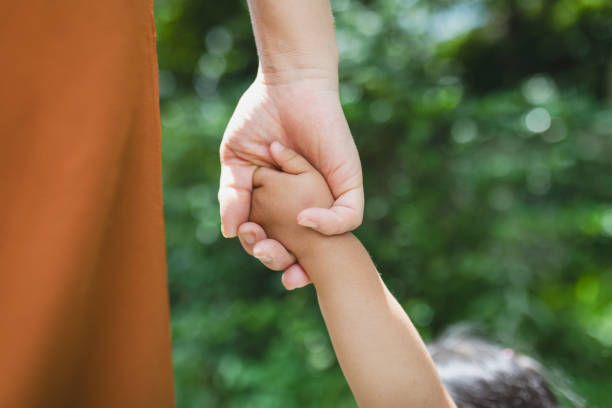 公園でお互いの手を握り合う母と娘 - 人間の手 ストックフォトと画像