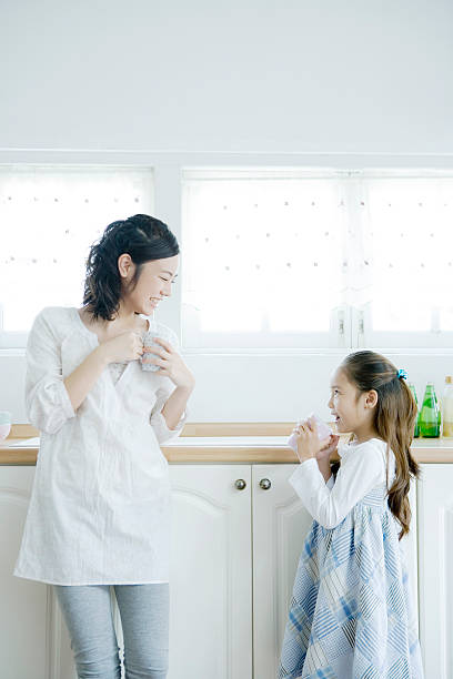 mother and daughter holding mug in hand - alleen japans stockfoto's en -beelden