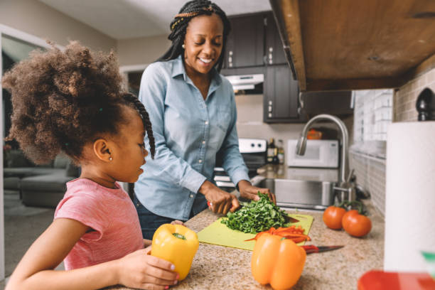moeder en dochter maken een salade - afro amerikaanse etniciteit stockfoto's en -beelden