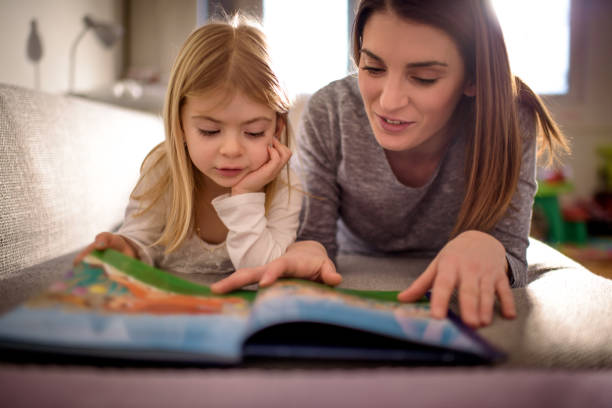 mother and daughter - child reading imagens e fotografias de stock