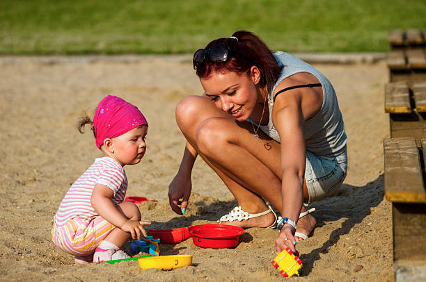Mother and daughter playing in sandbox stock photo