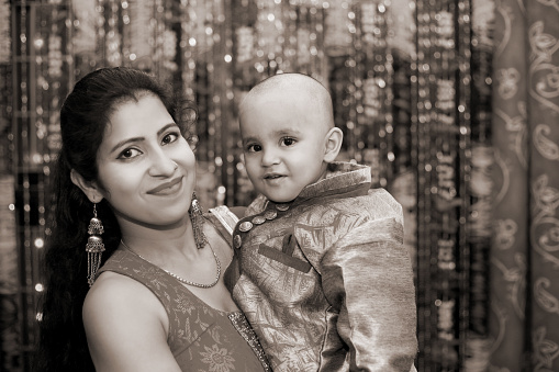 Close-up portrait of loving mother and daughter against floral decorative background on Diwali festival.