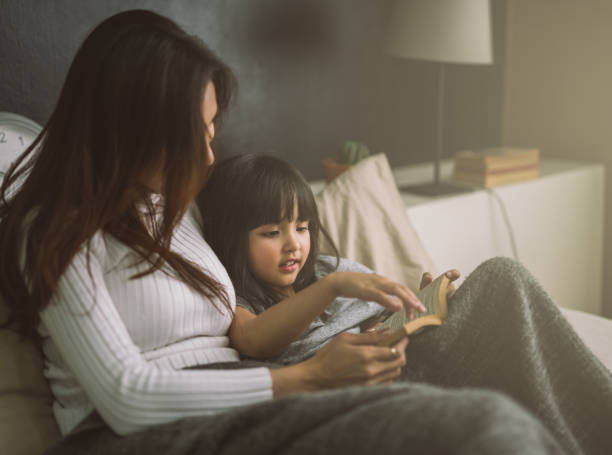 mother and daughter reading book at home in the bedroom mother and daughter reading book at home in the bedroom bed time story books for kids stock pictures, royalty-free photos & images