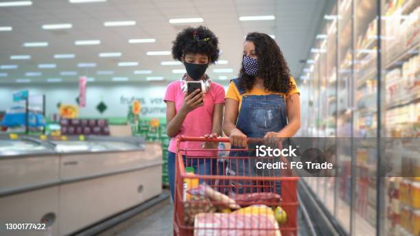 Mother and daughter shopping together in the supermarket - wearing face mask