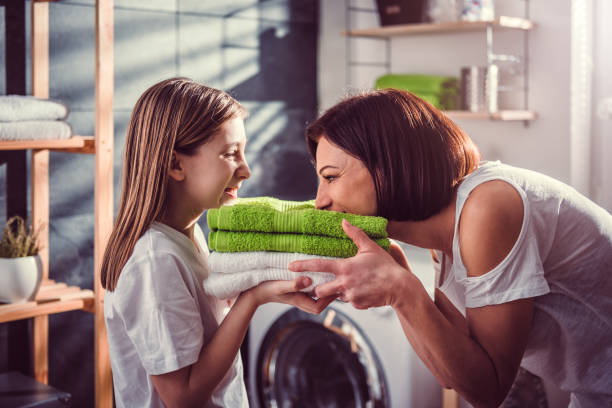 Mother and daughter smelling fresh towels Mother and daughter smelling fresh green towels at laundry room dryer stock pictures, royalty-free photos & images