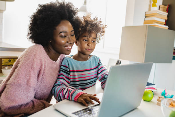 Mother and daughter studying with laptop African American mother is teaching her daughter are using laptop at home together parent stock pictures, royalty-free photos & images