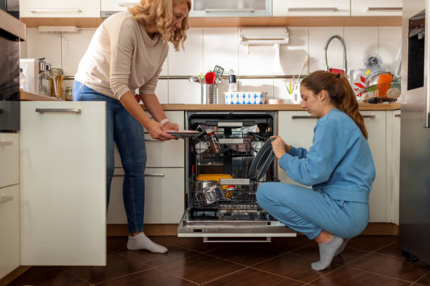 Mother And Daughter Unloading Dishwasher stock photo