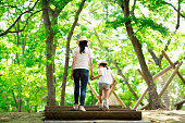 森の階段で手をつないで歩く母と娘