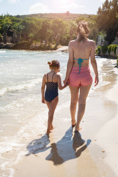 Mother and daughter walking on the beach stock photo