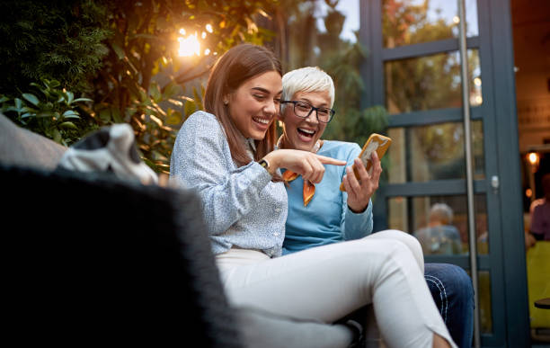 mother and daughter watching cell phone, smiling and laughing stock photo
