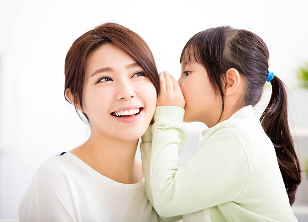 mother and daughter whispering gossip mother and daughter whispering gossip asian mother talking with daughter stock pictures, royalty-free photos & images