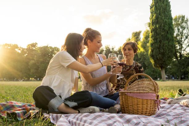 Mother and daughters drinking wine in a park during a picnic stock photo