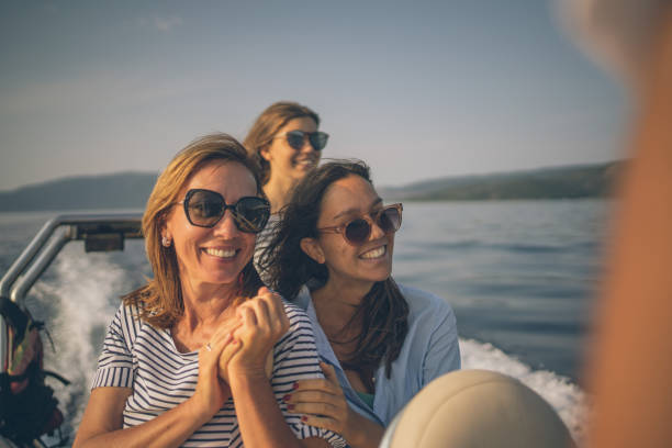 Mother and daughters relax on motorboat at sunrise stock photo