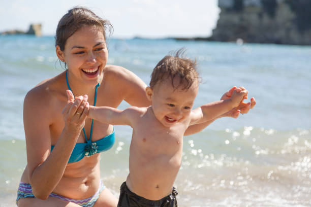 A mother and her son are playing on a beach stock photo