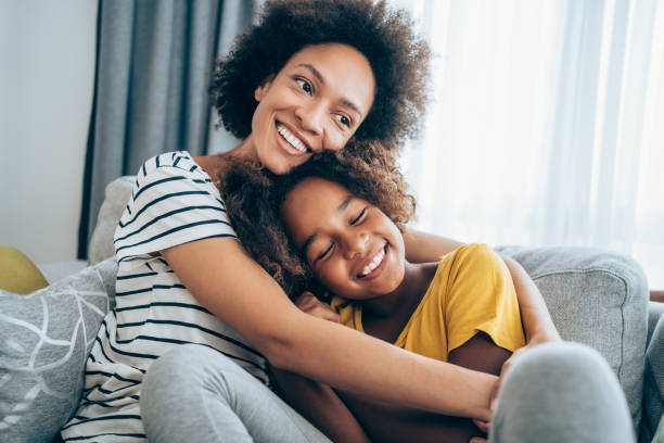 Mother and little daughter at home. Lovely mother embracing her cute daughter on the sofa at home. happy stock pictures, royalty-free photos & images