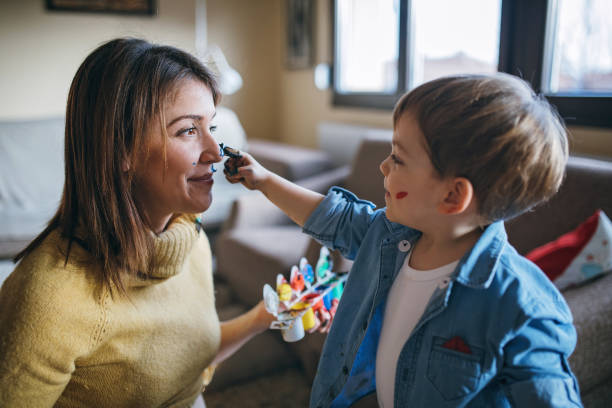 Mother and son having fun with finger paint Little boy painting his pregnant mother with finger paint tempera painting stock pictures, royalty-free photos & images