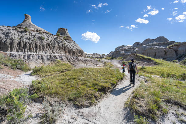Mother and Son Hiking in Badlands of Dinosaur Provincial Park in Alberta, Canada Mother and Son Hiking in Badlands of Dinosaur Provincial Park in Alberta, Canada. It is a beautiful summer sunny day. They are bonding while hiking in the park’s footpath. fossil site stock pictures, royalty-free photos & images
