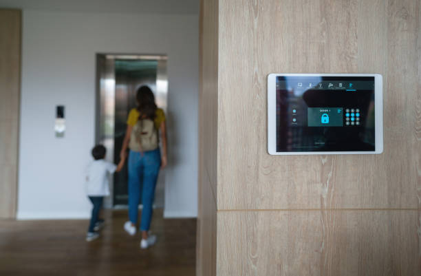 Mother and son leaving the house and locking the door using an automated security system stock photo