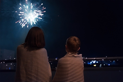 Mother and son looking at New Year celebration fireworks in nigh
