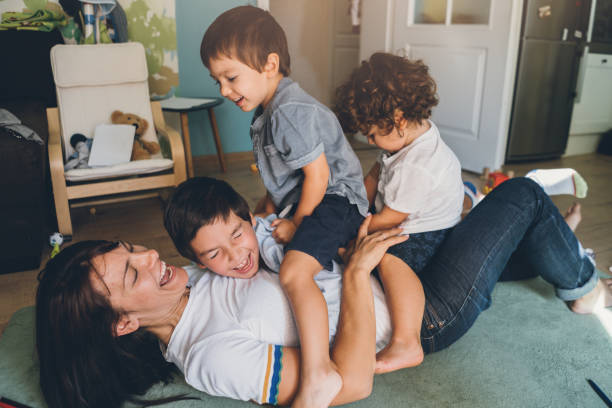 Mother and three boys playing Mother and three boys playing on the floor tickling beautiful women pictures stock pictures, royalty-free photos & images
