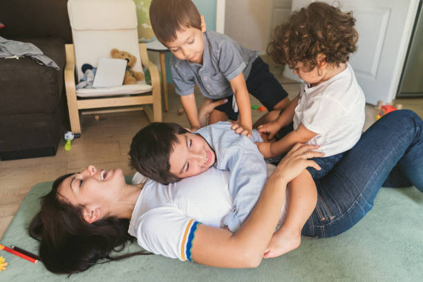 Mother and three boys playing Mother and three boys playing on the floor tickling beautiful women pictures stock pictures, royalty-free photos & images