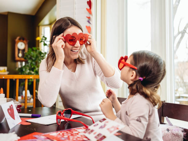 Mother and young daughter crafting for Valentine's Day stock photo