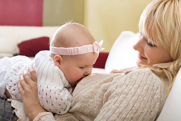 Mother breast feeding her baby girl at home stock photo