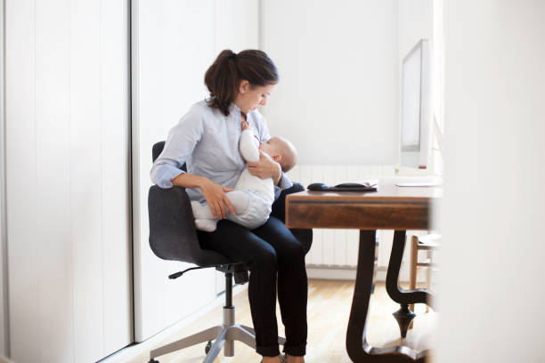 Mother breastfeeding her baby at work stock photo