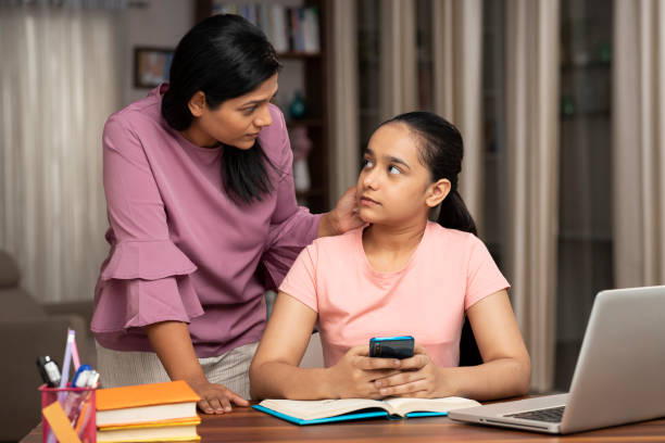 Mother Catches Daughter Using Phone while studying stock photo