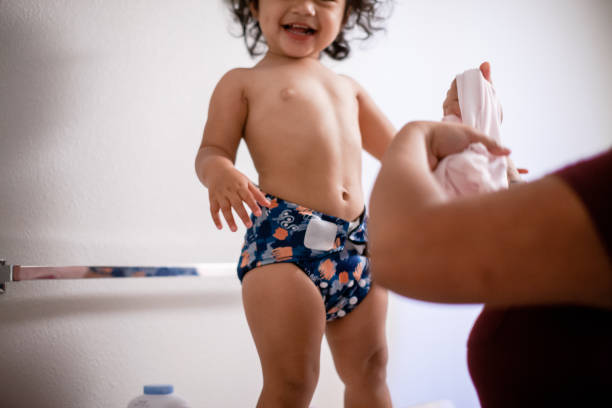 Mother Changing Baby Girl into Reusable Diaper stock photo