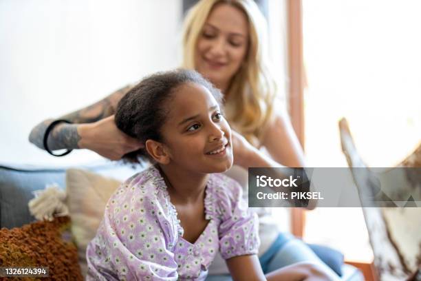 Mother combing curly hair of a daughter