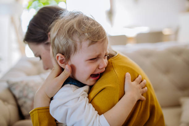 Mother consoling her little upset daughter at home. stock photo