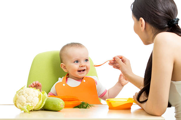 mother feeding baby girl stock photo