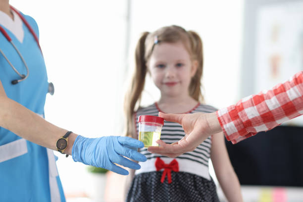 Mother giving doctor jar of urine analysis in front of little girl closeup stock photo