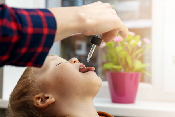 mother giving vitamin drops with dropper to her child. dietary supplements for kids stock photo
