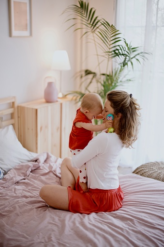 Mother playing with her baby daughter in the bedroom